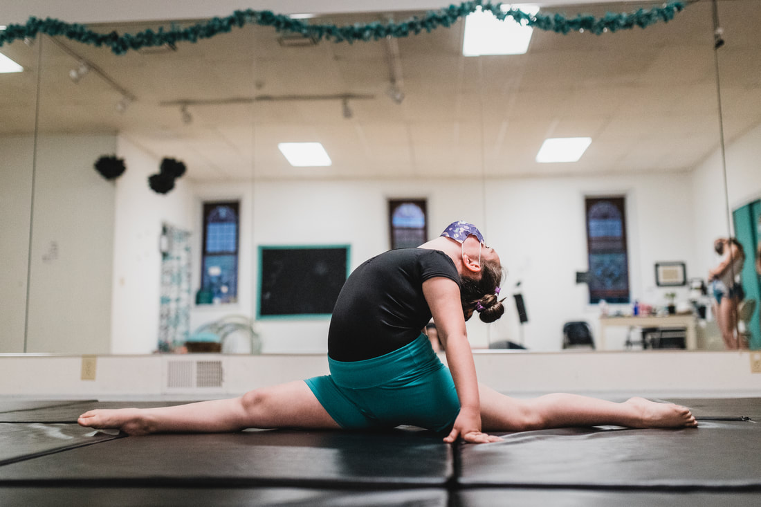 A dancer holding an acro split-and-backbend pose on the mats