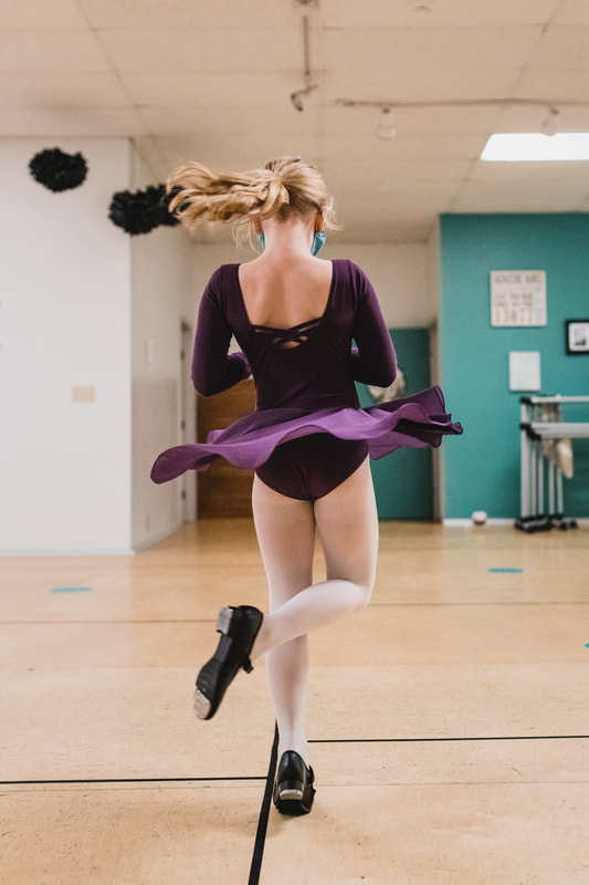 A dancer in a purple leotard spinning across the studio floor