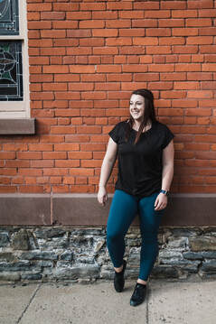 Meghan Libous, owner and instructor at Signature Dance Company, smiling against a brick wall