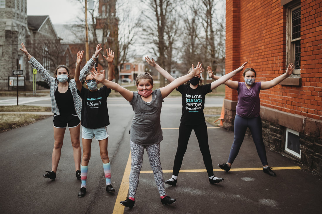 Signature Dance Company students outside, arms raised high in joyful poses