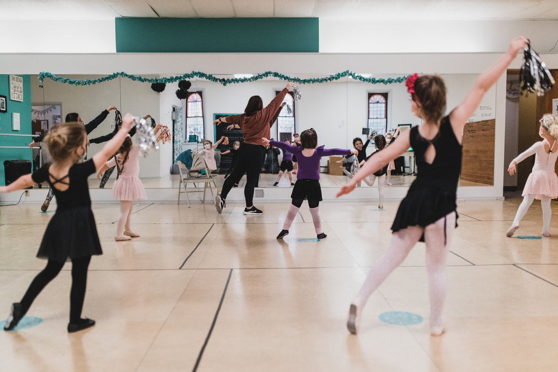 Young dancers moving across the studio floor in a ballet class at Signature Dance Company